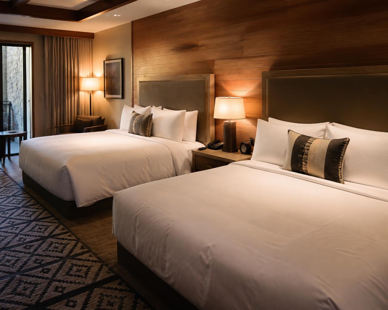 Guest room in an Amarillo hotel with two made beds and warm lamp lighting